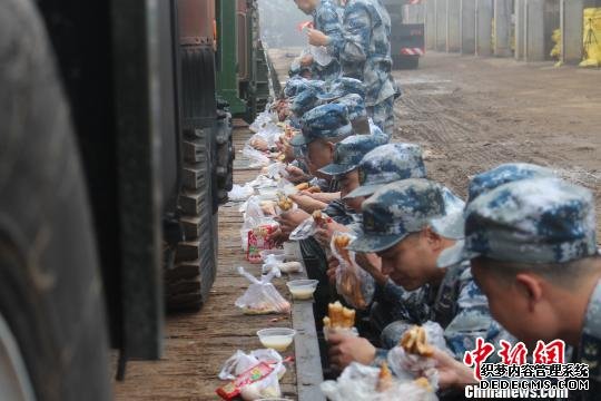 装载完毕，官兵们在铁路装载平板边席地而坐吃早餐。　凡超 摄