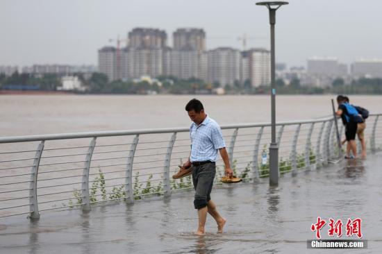 7月7日，市民从长江南京下关段被淹的滨江步道上经过。当日，江苏省防汛防旱指挥部办公室发布的信息显示，受长江上中游来水影响，南京站潮位上涨，超警戒水位。中新社记者 泱波 摄