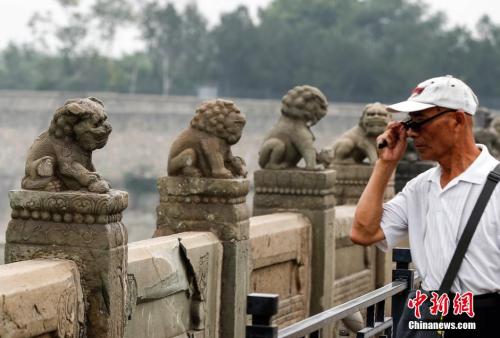 资料图：2014年7月7日中午，一名老人在北京卢沟桥凝视着上面的狮子。当日是“全民族抗战爆发77周年”纪念日，不少民众前往北京卢沟桥进行纪念活动。 中新社发 张浩 摄